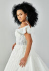 Bride wearing a ruffled off-shoulder ball gown with beaded corset bodice and embroidered jacquard skirt from Casa Reina Bridal Collection
