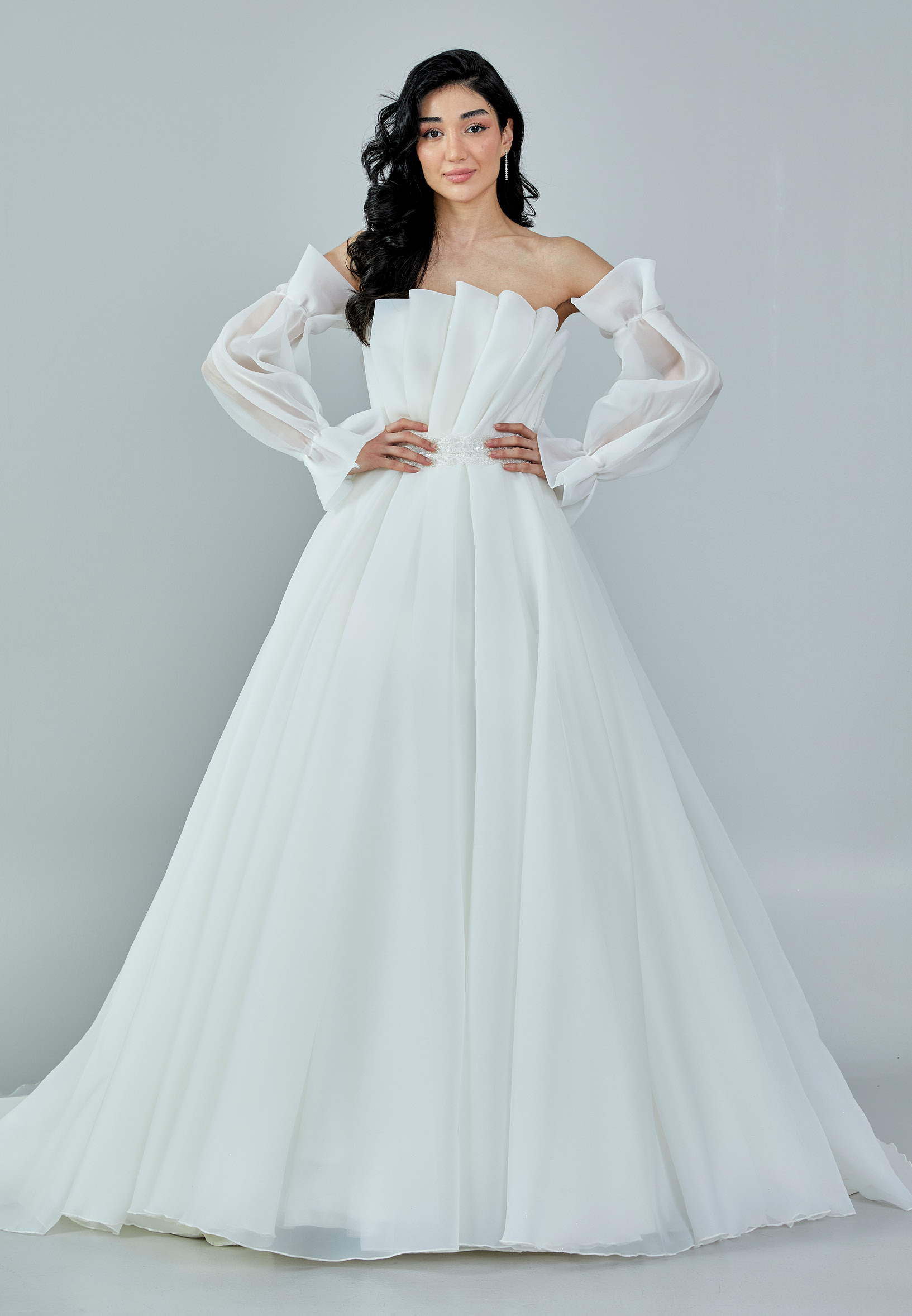 Bride wearing an off-shoulder sculpted organza ball gown with voluminous sleeves and pleated bodice from Casa Reina Bridal Collection