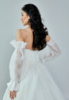 Bride wearing an off-shoulder sculpted organza ball gown with voluminous sleeves and pleated bodice from Casa Reina Bridal Collection