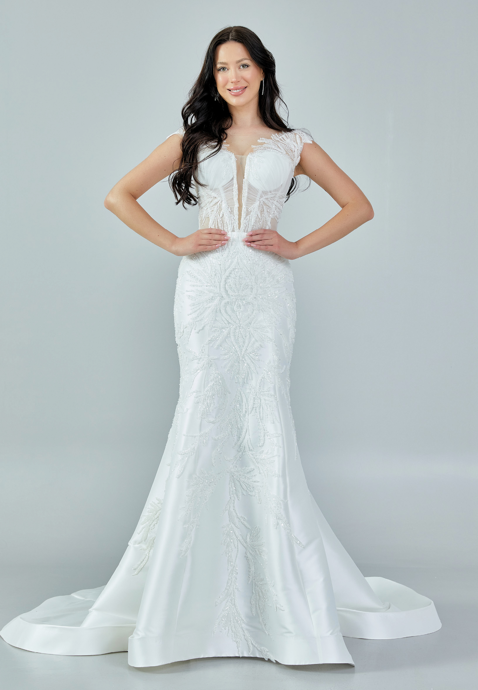 Bride wearing a beaded illusion mermaid gown with cap sleeves and satin skirt from Casa Reina Bridal Collection