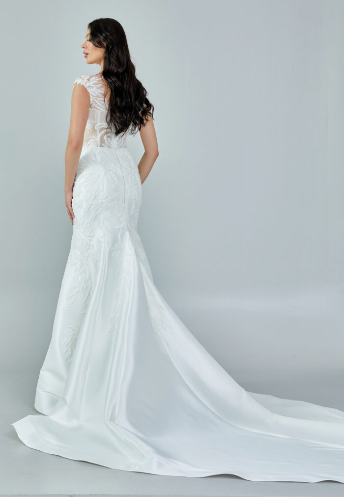 Bride wearing a beaded illusion mermaid gown with cap sleeves and satin skirt from Casa Reina Bridal Collection