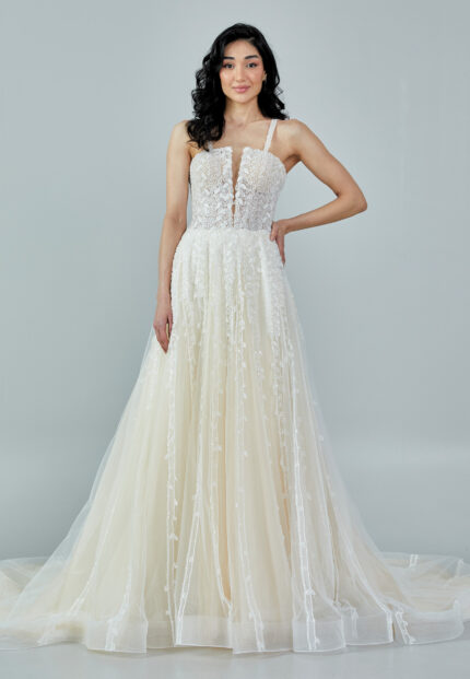 Bride wearing a romantic lace and tulle gown with deep illusion neckline and flowing A-line skirt from Casa Reina Bridal Collection
