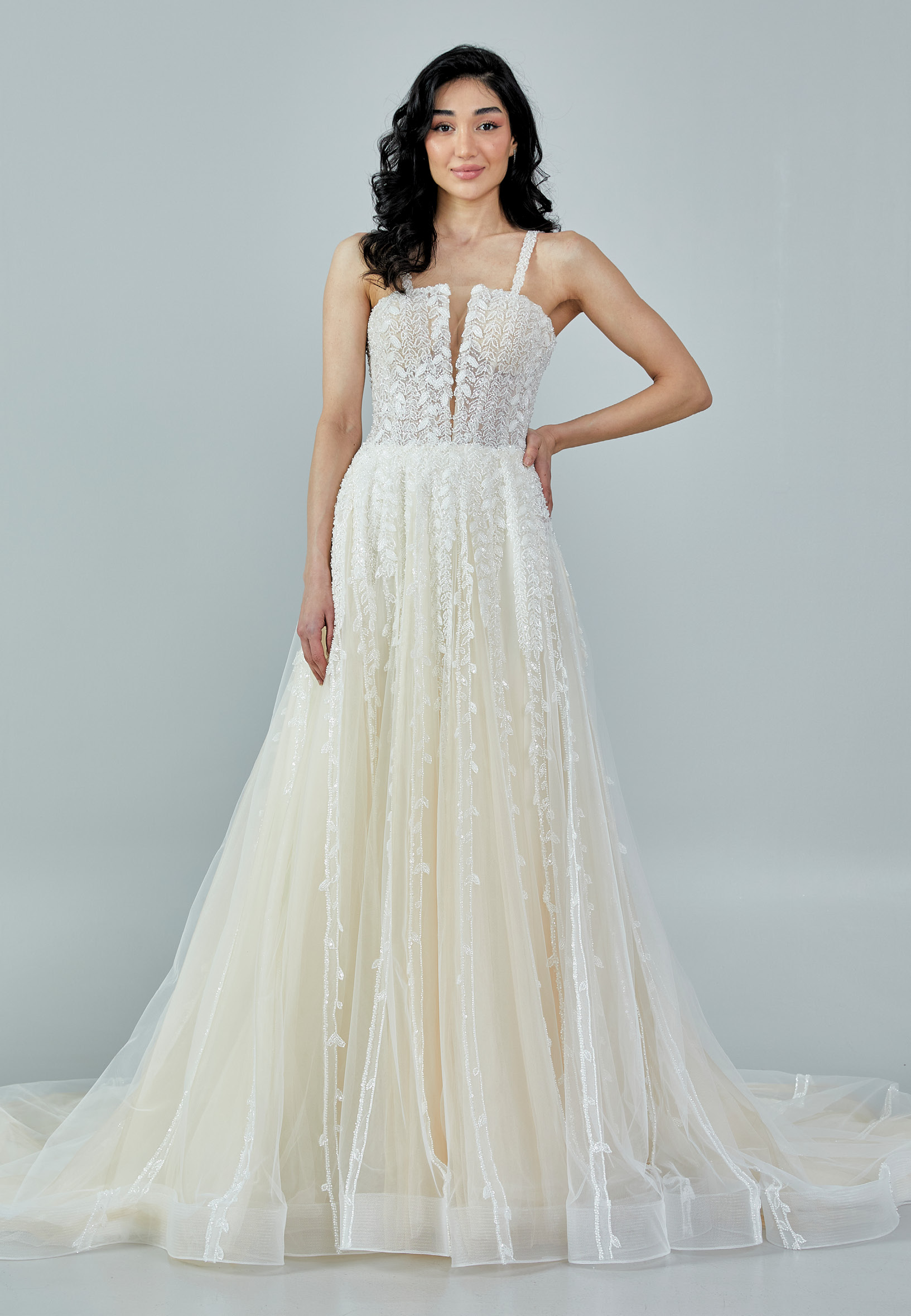 Bride wearing a romantic lace and tulle gown with deep illusion neckline and flowing A-line skirt from Casa Reina Bridal Collection