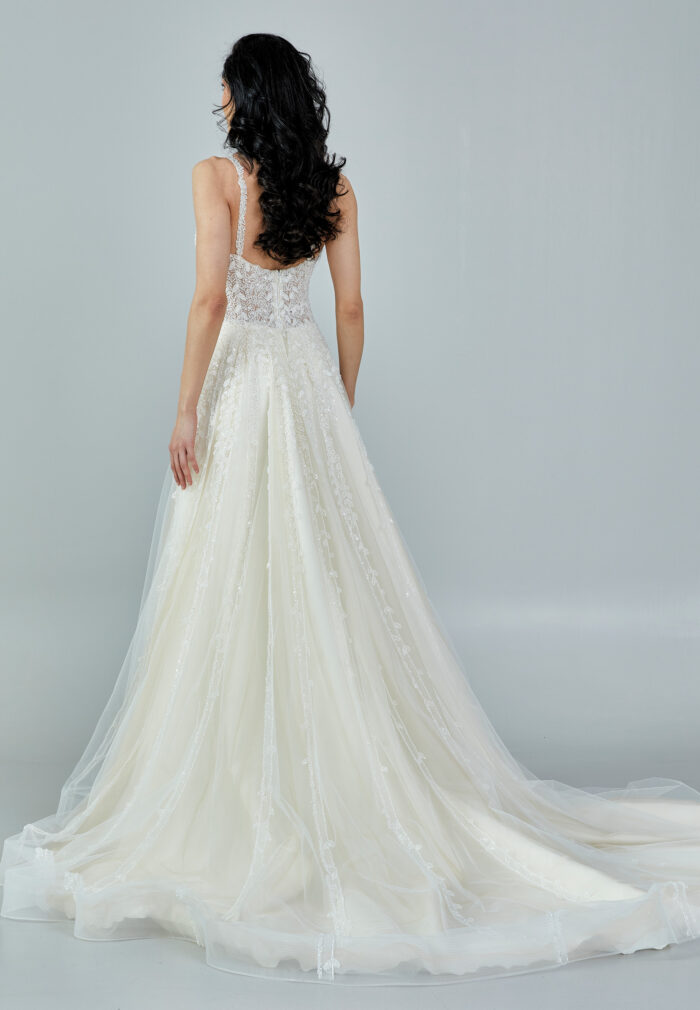Bride wearing a romantic lace and tulle gown with deep illusion neckline and flowing A-line skirt from Casa Reina Bridal Collection