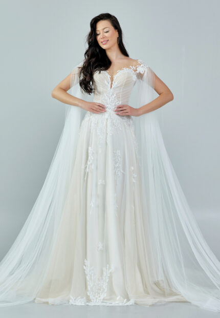 Bride wearing an ethereal tulle gown with illusion bodice, lace embroidery, and flowing cape sleeves from Casa Reina Bridal Collection