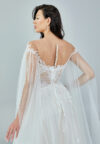 Bride wearing an ethereal tulle gown with illusion bodice, lace embroidery, and flowing cape sleeves from Casa Reina Bridal Collection
