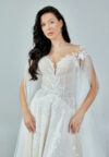 Bride wearing an ethereal tulle gown with illusion bodice, lace embroidery, and flowing cape sleeves from Casa Reina Bridal Collection