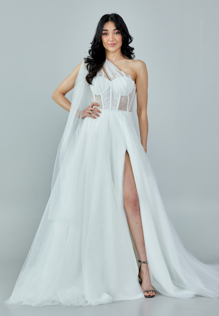 Bride wearing a one-shoulder corseted gown with draped tulle and thigh-high slit from Casa Reina Bridal Collection