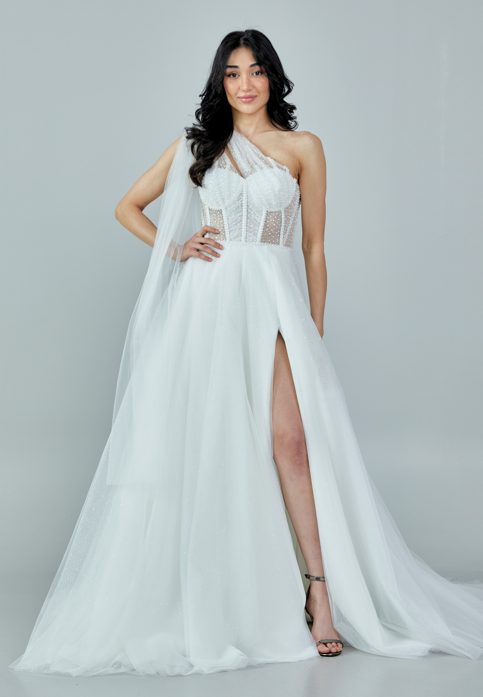 Bride wearing a one-shoulder corseted gown with draped tulle and thigh-high slit from Casa Reina Bridal Collection