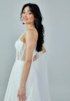 Bride wearing a one-shoulder corseted gown with draped tulle and thigh-high slit from Casa Reina Bridal Collection