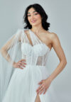 Bride wearing a one-shoulder corseted gown with draped tulle and thigh-high slit from Casa Reina Bridal Collection