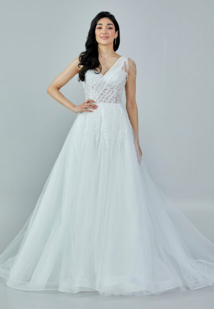 Bride wearing a beaded illusion A-line gown with draped shoulder detail and layered tulle skirt from Casa Reina Bridal Collection