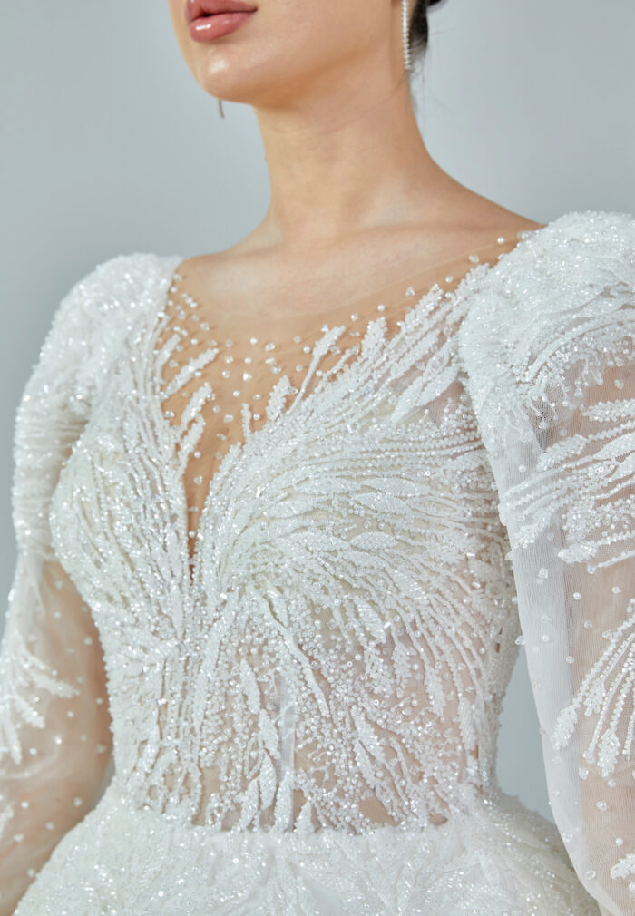 Bride wearing a regal embroidered ballgown with illusion long sleeves and crystal bead detailing from Casa Reina Bridal Collection