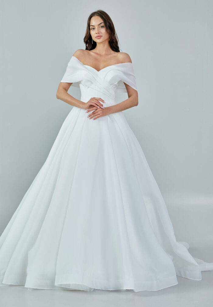 Bride wearing an off-shoulder organza ball gown with draped bodice and full skirt from Casa Reina Bridal Collection