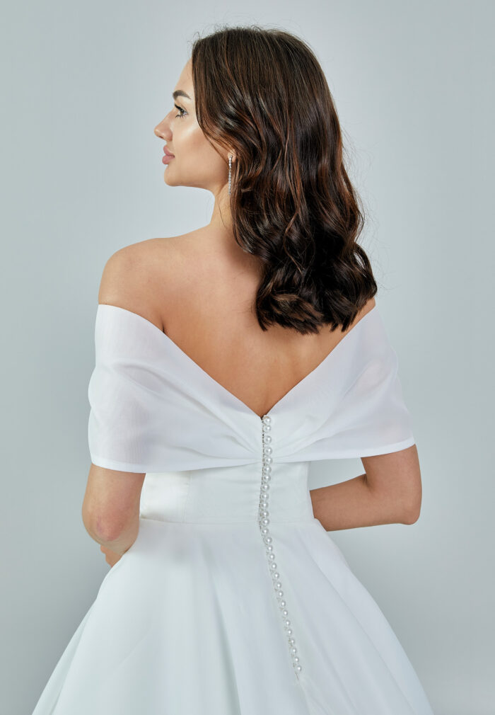 Bride wearing an off-shoulder organza ball gown with draped bodice and full skirt from Casa Reina Bridal Collection