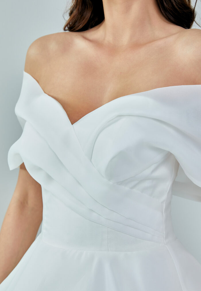 Bride wearing an off-shoulder organza ball gown with draped bodice and full skirt from Casa Reina Bridal Collection