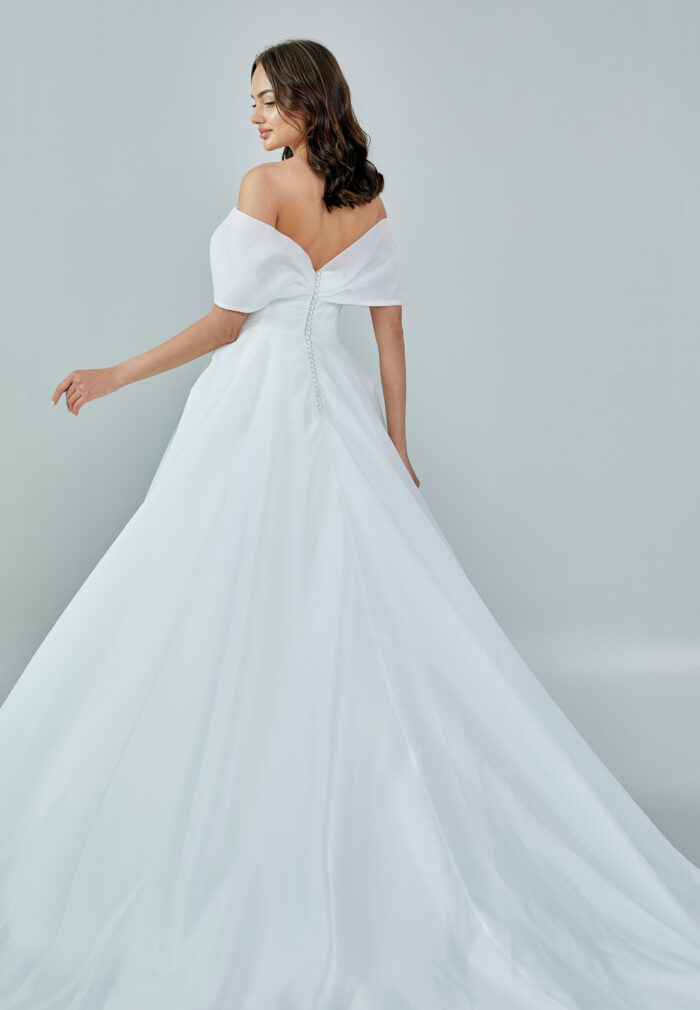 Bride wearing an off-shoulder organza ball gown with draped bodice and full skirt from Casa Reina Bridal Collection