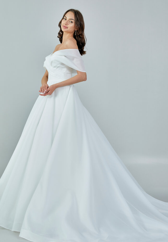 Bride wearing an off-shoulder organza ball gown with draped bodice and full skirt from Casa Reina Bridal Collection