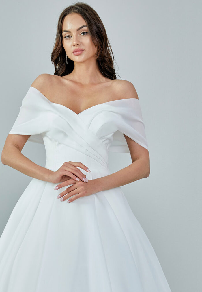 Bride wearing an off-shoulder organza ball gown with draped bodice and full skirt from Casa Reina Bridal Collection