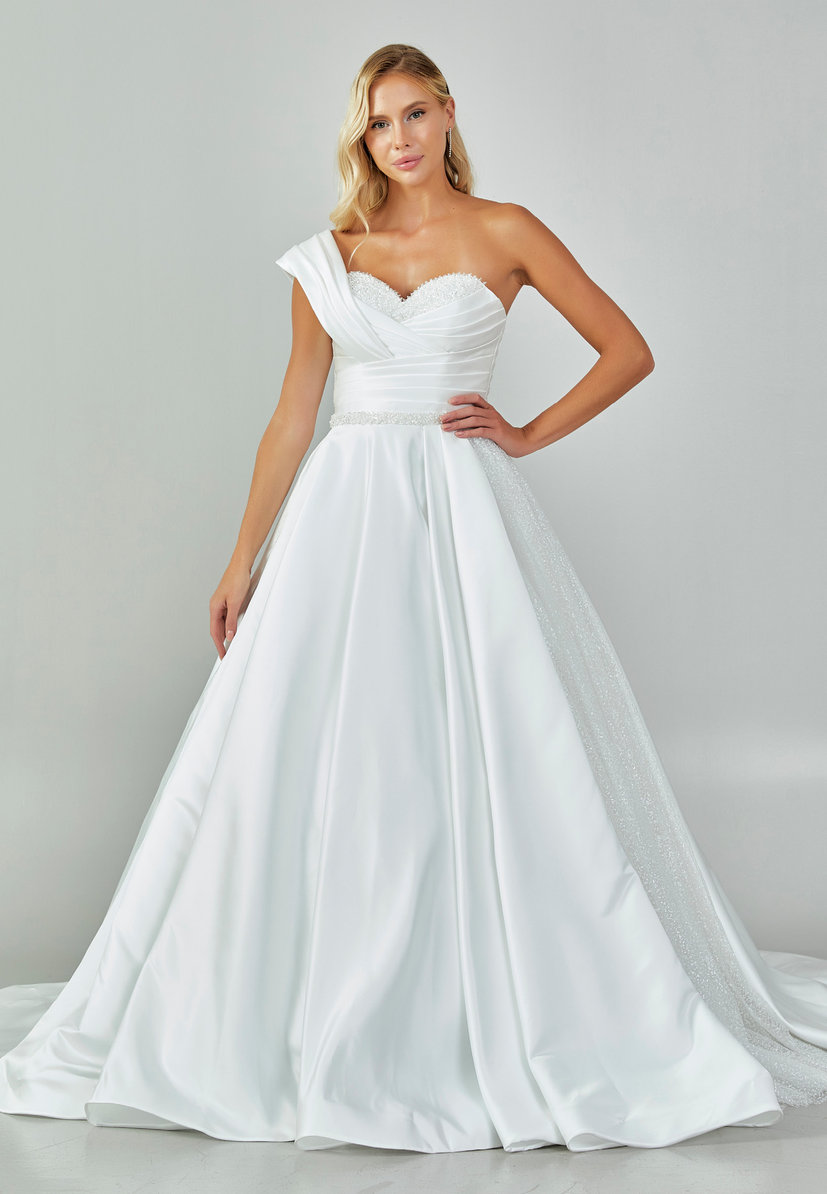 Bride wearing an asymmetrical satin ballgown with draped shoulder and beaded sweetheart neckline from Casa Reina Bridal Collection