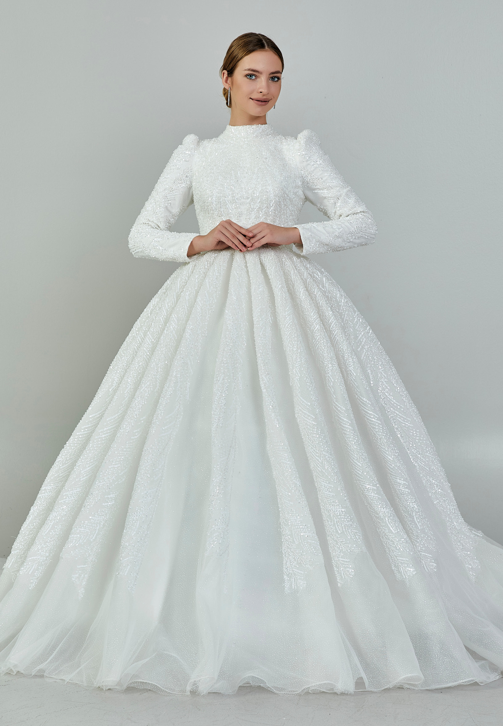 Bride wearing a high-neck long sleeve ball gown with hand-beaded detailing and cathedral train from Casa Reina Bridal Collection