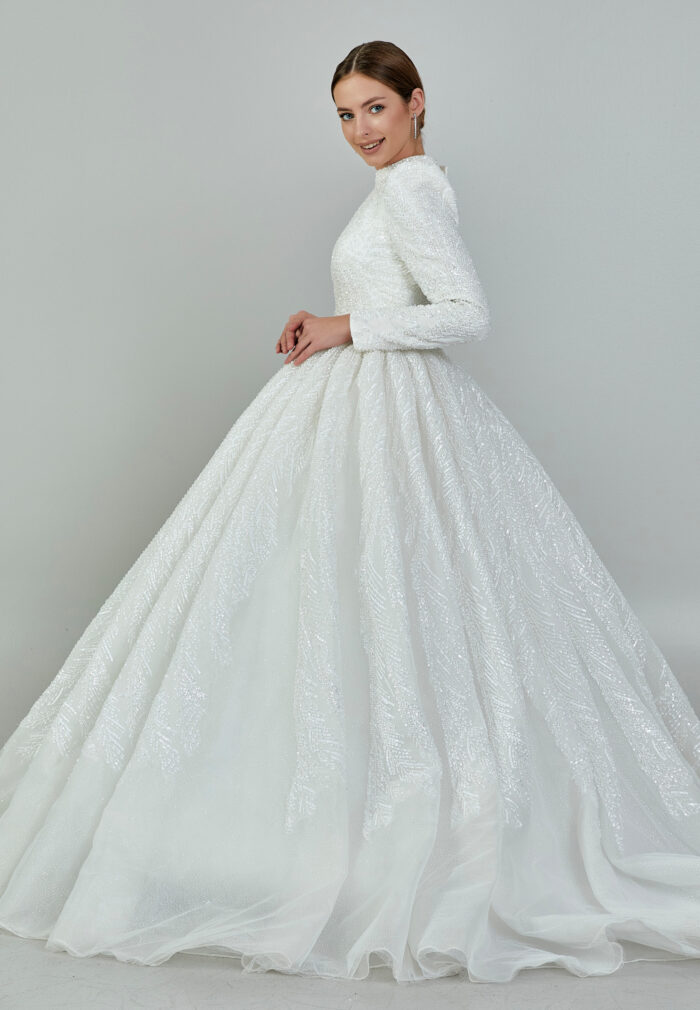 Bride wearing a high-neck long sleeve ball gown with hand-beaded detailing and cathedral train from Casa Reina Bridal Collection