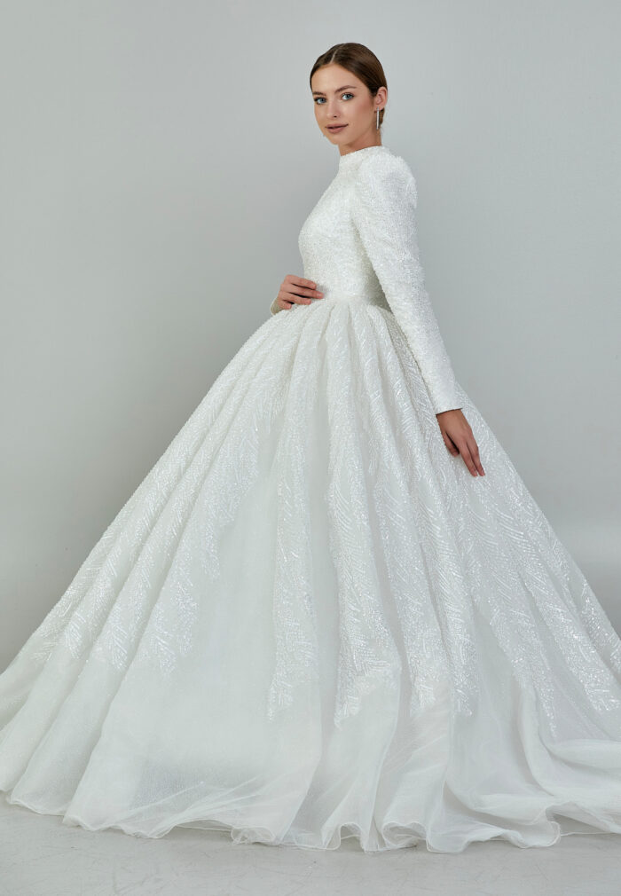 Bride wearing a high-neck long sleeve ball gown with hand-beaded detailing and cathedral train from Casa Reina Bridal Collection
