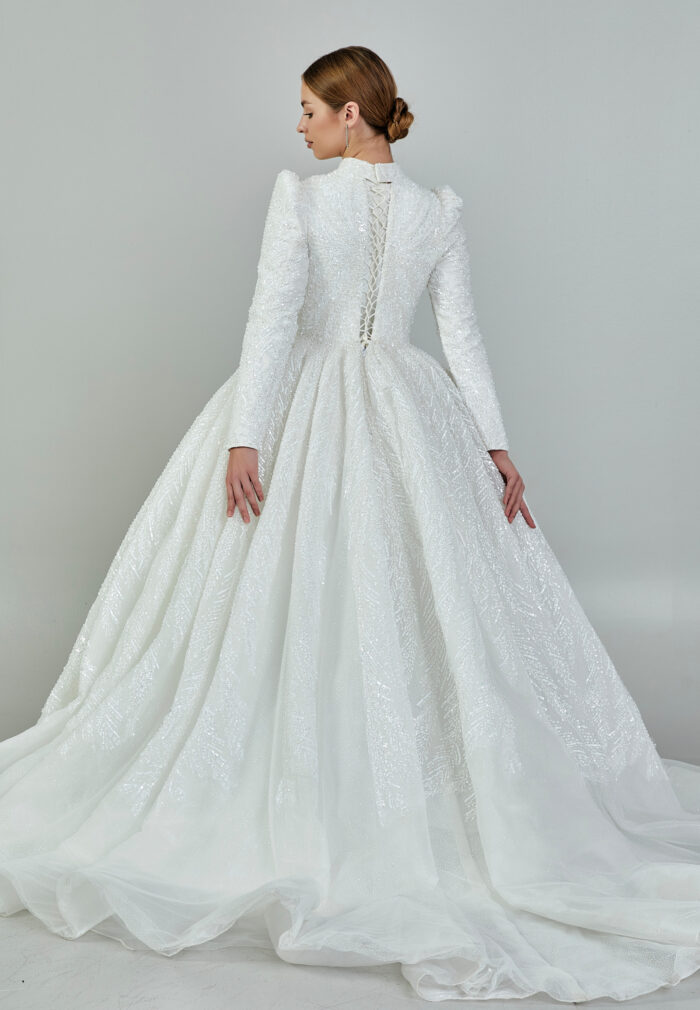 Bride wearing a high-neck long sleeve ball gown with hand-beaded detailing and cathedral train from Casa Reina Bridal Collection