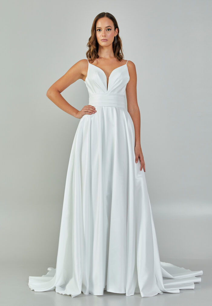Bride wearing a minimalist satin A-line gown with plunging neckline and structured waist from Casa Reina Bridal Collection