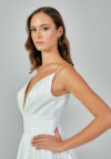 Bride wearing a minimalist satin A-line gown with plunging neckline and structured waist from Casa Reina Bridal Collection