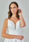 Bride wearing a minimalist satin A-line gown with plunging neckline and structured waist from Casa Reina Bridal Collection