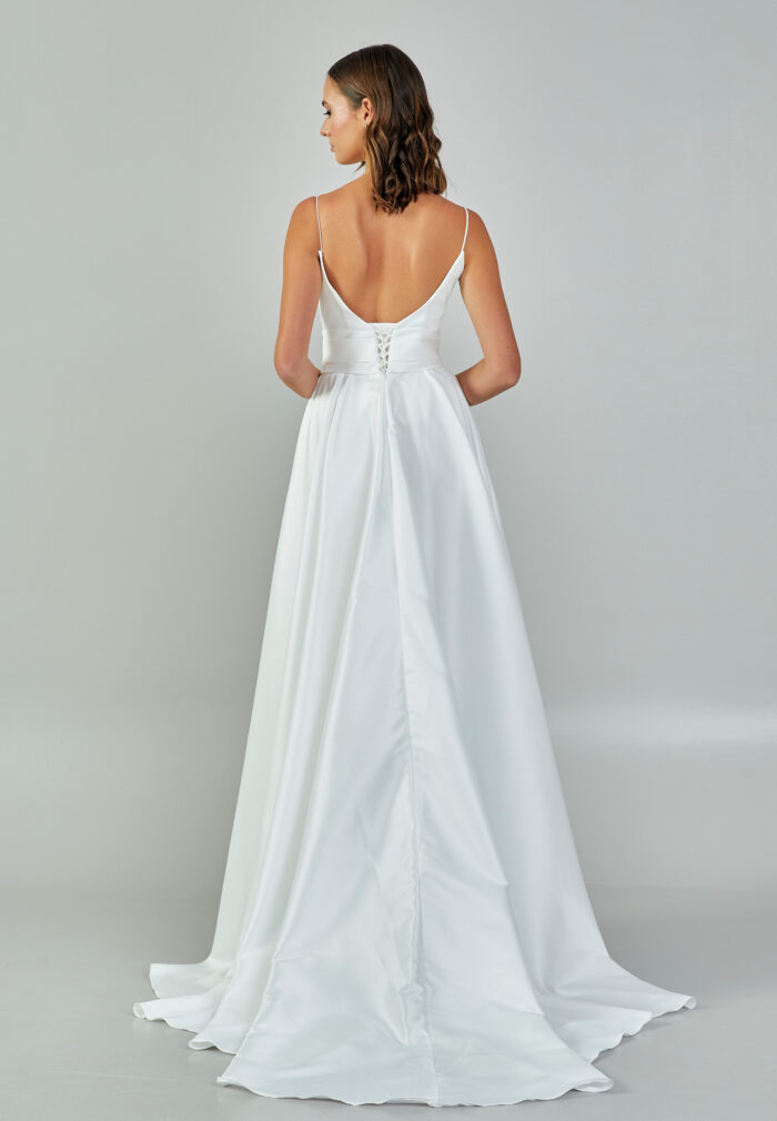 Bride wearing a minimalist satin A-line gown with plunging neckline and structured waist from Casa Reina Bridal Collection