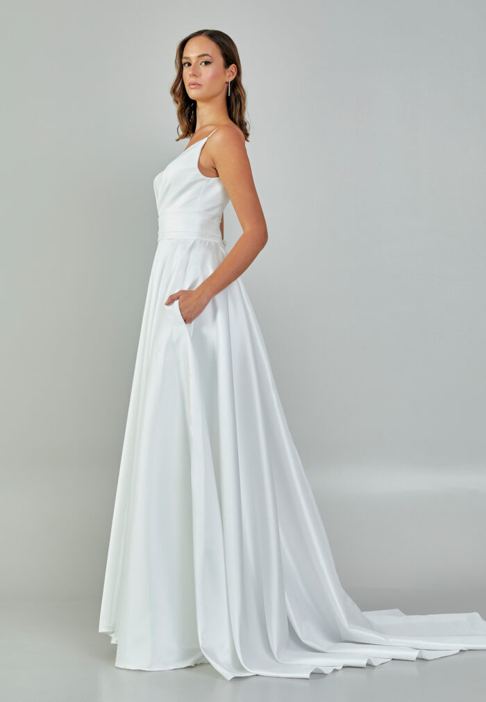 Bride wearing a minimalist satin A-line gown with plunging neckline and structured waist from Casa Reina Bridal Collection