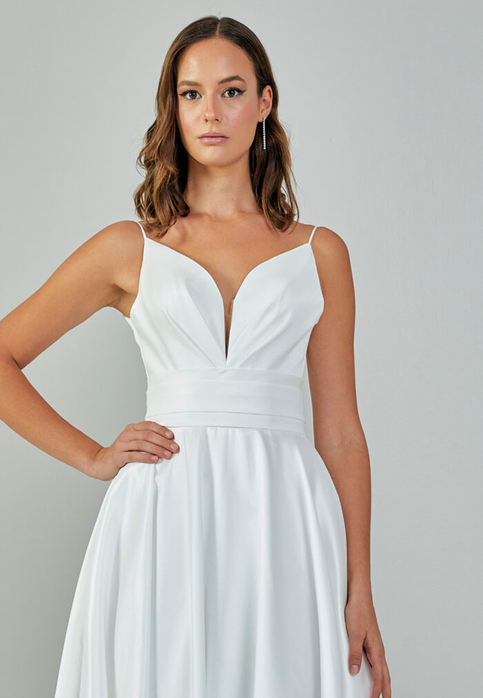 Bride wearing a minimalist satin A-line gown with plunging neckline and structured waist from Casa Reina Bridal Collection