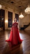 Red one shoulder evening gown with beaded bodice and tulle skirt with cape