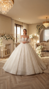 Bride wearing a voluminous ivory floral lace ball gown with detachable puff sleeves in a luxurious, flower-decorated interior.